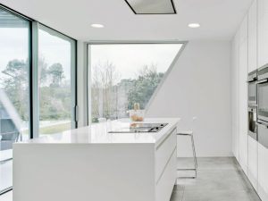Iluminación general con grandes ventanas en una cocina blanca.